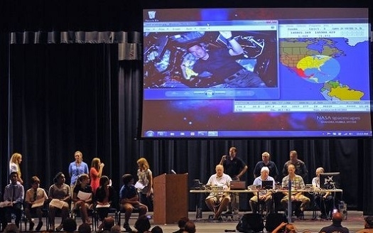 Students take their turn stepping up to the microphone on an auditorium stage.