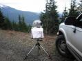 K7MDL/R 10GHz setup with towel to keep the light rain and cold wind off.  Pointed south at N7EPD and KB7DQH/R on Poch's Peak in CN96 (about 130km).   This is Sunday afternoon on Green Mountain in CN98 at 2950ft.  The snow topped mountain to the left is Mt. Pilchuck with the often visited "bench" area visible just to the immediate left of the dish.   Everett is about 90deg to the right from this angle.   The black box on the back is velcro'd in place and is a 15.36MHz TCXO connected into the directional coupler to act as a reasonably accurate marker generator at 10368.088MHz.  I added a crystal oven to the brick PLO last week, and after a short warm up I found the stations quickly within 3 KHz of where I expected. W7NBH in eastern Washington CN96 came in strong over the Cascade mountain range on this angle on 6M through 1296, working the bounce off Mt. Rainer in CN96.  It was mostly dry except when we wanted to work 10GHz!
