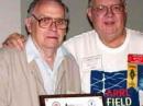 Harry Lewis, W7JWJ (left), receives the ARRL Certification and Continuing Education Mentor/Instructor of the Year Award in 2005 from then-Northwestern Division Director Greg Milnes, W7OZ (SK).