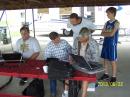 W7REA, WY7JR, KG7EAI, and WY7JB are setting up the computers as a youngster looks on.