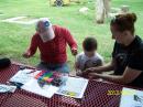 KF7CBC teaches a visiting youngster and mom how to make a bracelet with their name in beads designed to look like Morse code.