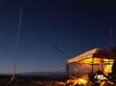 A cozy shack at night, with the antenna all aglow