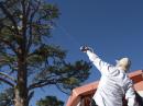 Myron, WV0H, uses his slingshot and fishing reel to shoot a pilot wire over tree branches. After a successful first attempt, the dipole was raised a few minutes later.