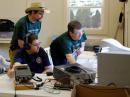 Nick Farlow, KB0YHT and Randy Wing, N0LD try to resolve a network communication challenge at the 6m/10m station.  Evert Hastie, KC0FUE continues making 10m contacts on paper.