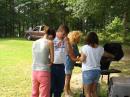 Brittney assists AF4NP say grace over the cooking as KF4IZU and Coleen cook.