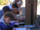 Scouts working the interactive Technician test, watching a video clip of Jay Leno competing text messengers against CW operators (the hams won!), using a computer Morse code translator and key, and Earl and Gene working contacts.