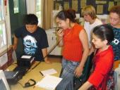 A girl speaking into a hand held microphone in a group of students inside.