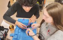 Two students working on a soldering kit together.