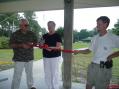 Wilmington (NC) City Councilwoman Margaret Haynes is about to cut a ribbon to kick off Field Day at 1800 UTC.  Holding the ribbon are (L) New Hanover School Board member Don Hayes and (R) Capt. Michael Hamby, KG4SRW, President of the Azalea Coast Amateur Radio Club
