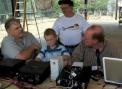 Ted Kreeger (AD5XK), left, talks with David Moore (N5ELI), rear and Tim Helgerson (KB7PGT), right, while Helgersons son, Drew checks out the operation of the rig. Photo by Larry Wagoner (N5WLW)