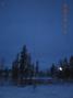 A picture of the antenna, tuner and radial system out in the snow.  My cabin is in the background.