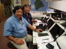 Robin Liu, AH6CP (left), and Ron Hashiro, AH6RH, at the SCD RACES operating position, grateful that the tsunami turned out to be non-destructive. [Mitch Pinkerton, KH6MP, Photo]