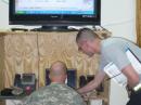 At a meeting of the Baghdad Amateur Radio Society, Sgt Owen Fuller watches SPC David Barns input a MARSgram for transmission back to the States. [Captain Jeffrey Hammer, N9NIC, Photo]