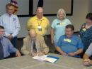 State Coordinator of the Virginia Department of Emergency Management Michael M. Cline (bottom left) watches State RACES Officer Mac McNeer, K4YEF, sign the new MOU between the Virginia Department of Emergency Management and Virginias ARRL Section. Next to McNeer is Virginia SEC Ron Sokol, K4KHZ and Virginia Section Manager Carl Clements, W4CAC. Back row, left to right: EOC Deputy Chief Operations Plans Section Terry Hebert, KG4GLS; Virginia Public Information Coordinator Joe Safranek, K4JJS; Virginia Assistant Section Manager Christine Sokol, K4CES, and Joy Safranek, W2JMS. [Photo Courtesy of Joe Safranek, K4JJS]