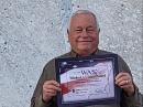 Al Ward, W5LUA, tient son certificat WAS devant sa parabole de 5 mètres. [Photo gracieuseté de W5LUA]