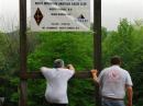 Luke KB1IIR and Dave N1CCB hold down the sign while Marc KB1OOO climbs out of the Mud Bowl