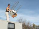 Before the contest, Carrie (W6TAI) hoists an equipment box and antenna system atop a camper.  This unit, which includes transverters and amplifiers for four microwave bands as well as antennas for six bands, weighs about 50 pounds, far more than you might suspect from the way she's swinging it around.