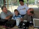 Ted Kreeger (AD5XK), left, talks with David Moore (N5ELI), rear and Tim Helgerson (KB7PGT), right, while Helgersons son, Drew checks out the operation of the rig. Photo by Larry Wagoner (N5WLW)